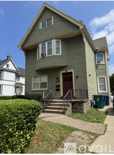 A two-story house with a red door and a small porch.