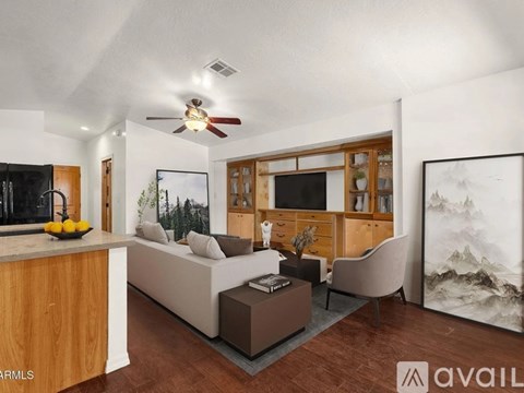 A living room with a couch, a chair, a coffee table, and a painting on the wall.