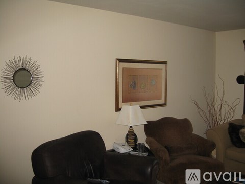 A living room with a brown leather couch and a framed picture on the wall.