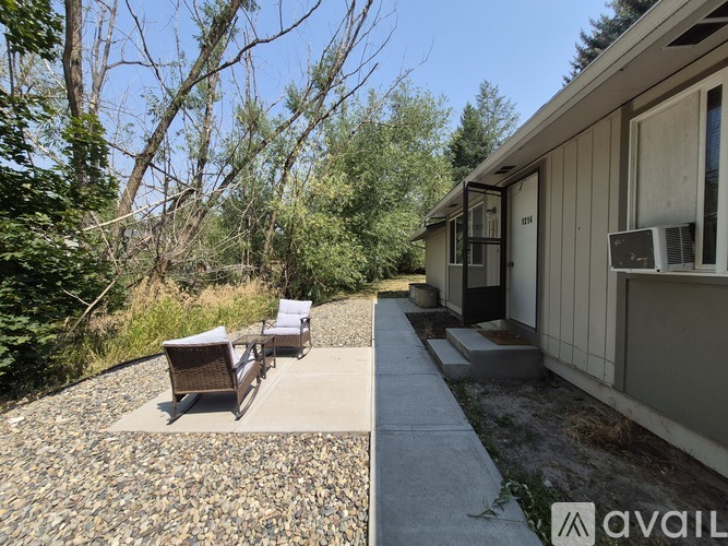 A patio area with chairs and a table is shown in front of a house.