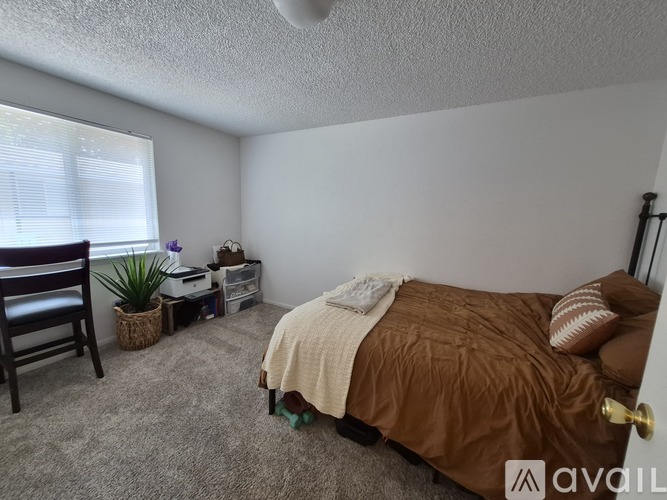 A bedroom with a bed, chair, and window.