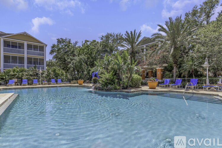 A pool surrounded by blue lounge chairs and palm trees.