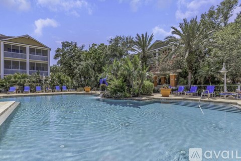 A pool surrounded by blue lounge chairs and palm trees.