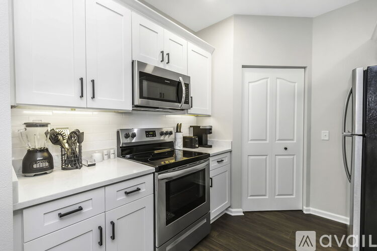 A kitchen with white cabinets and a black fridge.
