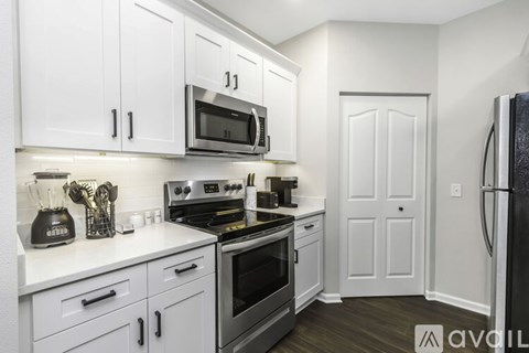 A kitchen with white cabinets and a black fridge.