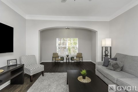 A living room with a grey couch, a black coffee table, and a television on the wall.