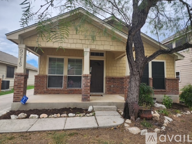 A house with a front yard and a tree in front of it.