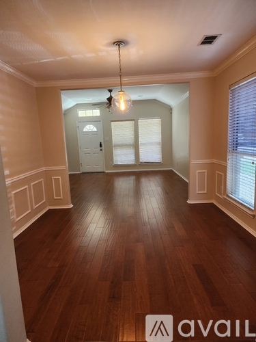 A room with wooden floors and a chandelier hanging from the ceiling.