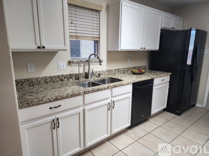 A kitchen with granite countertops and white cabinets.