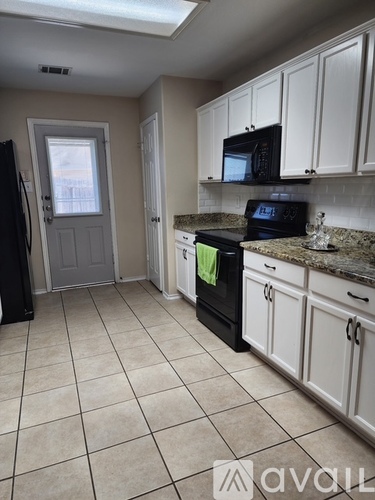 A kitchen with white cabinets and a black fridge.