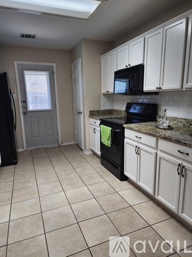 A kitchen with white cabinets and a black fridge.
