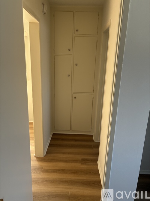 A white wardrobe with two doors is in a narrow hallway.