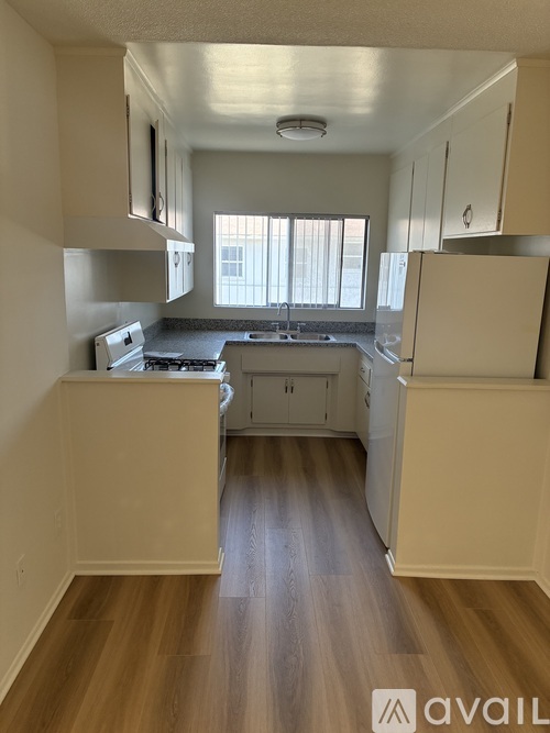 A kitchen with wooden floors and white appliances.
