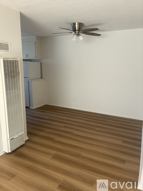 A room with a ceiling fan and a wooden floor.