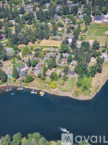 A bird's eye view of a residential area with houses, trees, and a body of water.