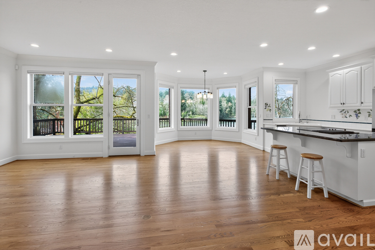 A spacious kitchen and living room with white cabinets and wooden floors.