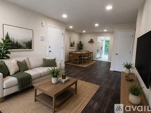 A living room with a white couch, a coffee table, and a painting on the wall.
