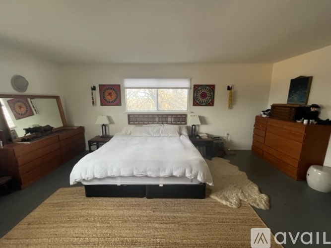 A bedroom with a large bed, a dresser, and a mirror.
