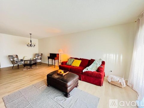 A living room with a red couch and a brown ottoman.