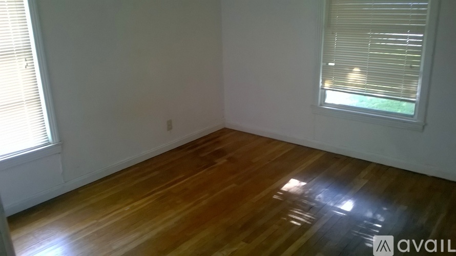 A room with wooden flooring and a window with blinds.