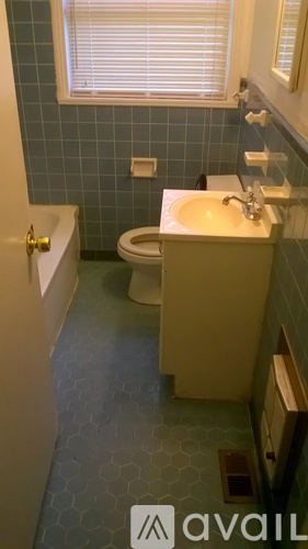 A bathroom with a toilet, sink, and a window.