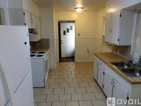 A kitchen with white appliances and wooden countertops.