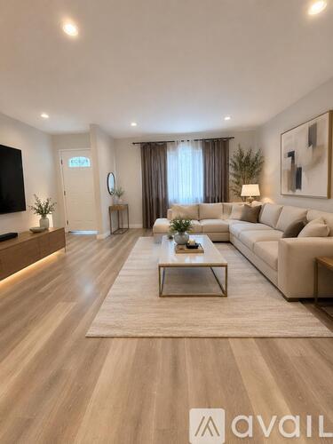 A modern living room with a large couch, a coffee table, and a flat-screen TV.
