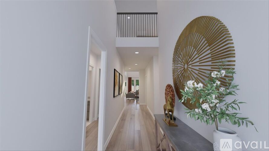 A long hallway with a round decorative piece on the wall and a vase of flowers on a table.