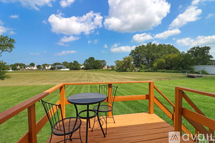 A patio with a table and chairs overlooking a grassy field.