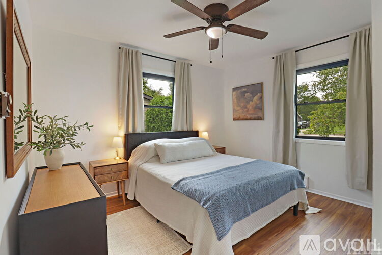 A bedroom with a bed, nightstand, and a ceiling fan.