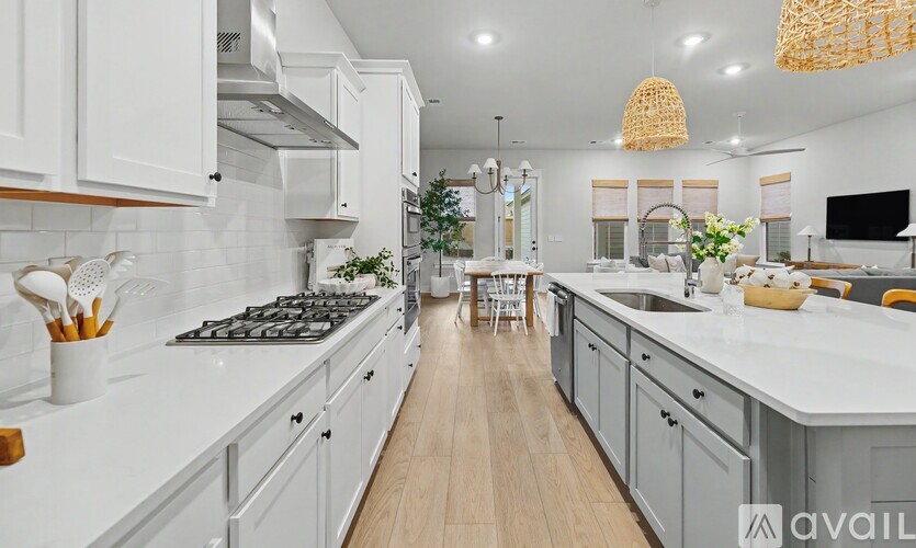 A modern kitchen with white cabinets and a wooden floor.