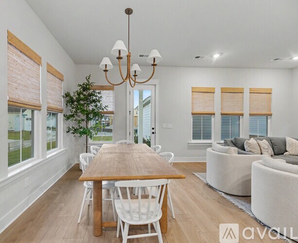 A dining room with a wooden table and white chairs.