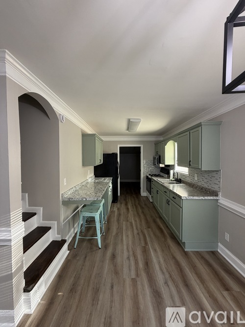 A kitchen with a countertop and stairs leading to the upper floor.
