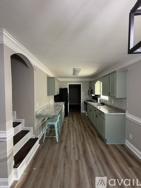 A kitchen with a countertop and stairs leading to the upper floor.