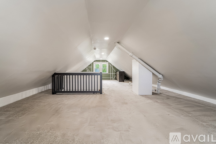 A baby crib sits in a spacious, empty room with a window in the background.