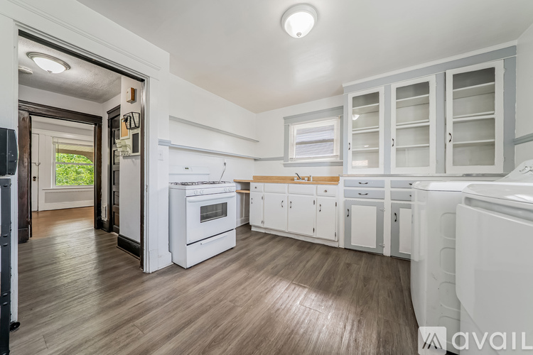 A kitchen with white appliances and wooden floors.