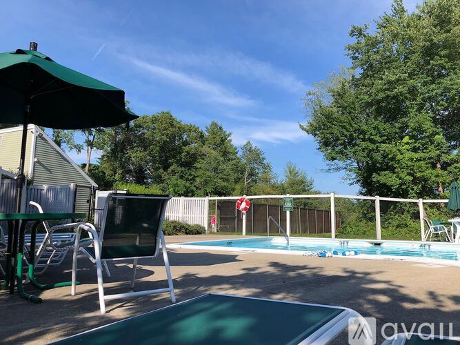 A pool with a green umbrella and a slide.