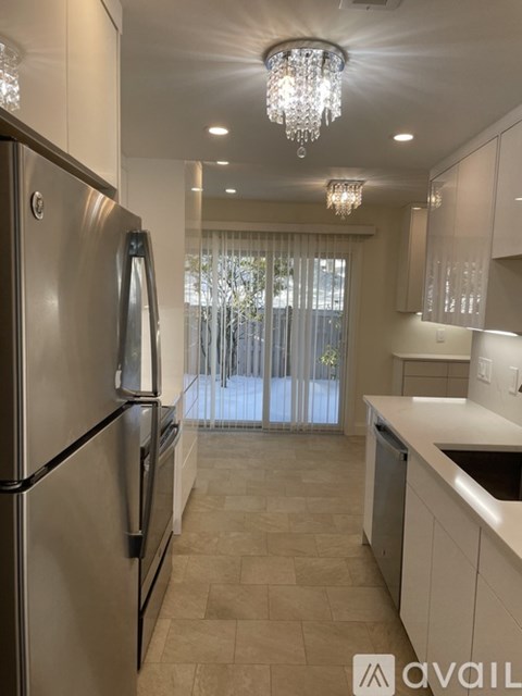 A kitchen with a stainless steel refrigerator and a chandelier.