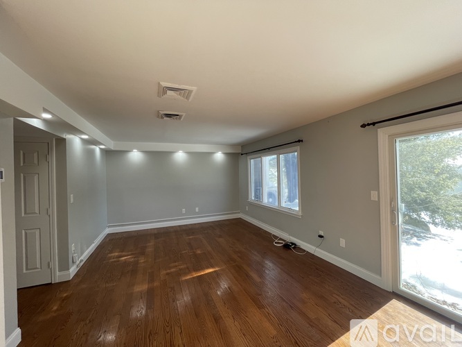 A room with wooden floors and a window showing trees outside.