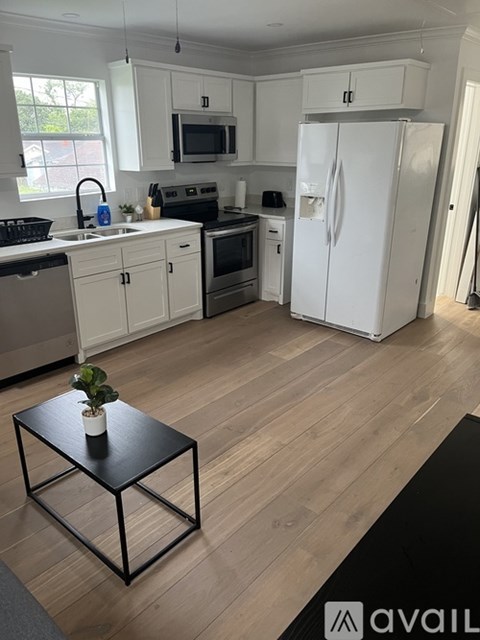 A kitchen with a white fridge, white cabinets, and a black table.