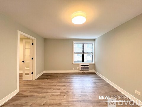 A spacious room with a window and a door leading to another room.