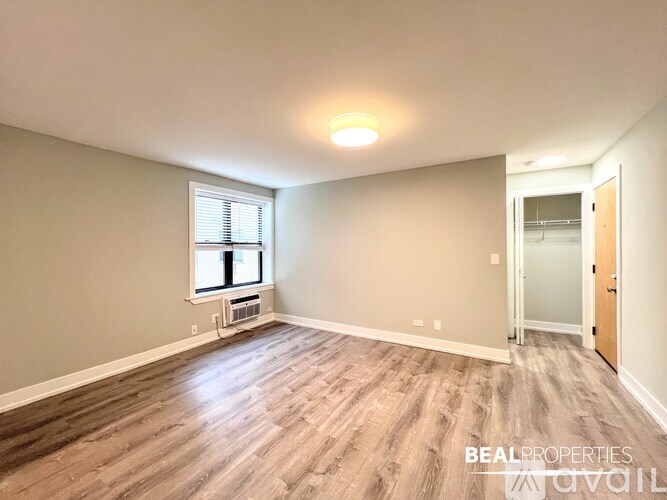 A room with wooden flooring and a window with blinds.