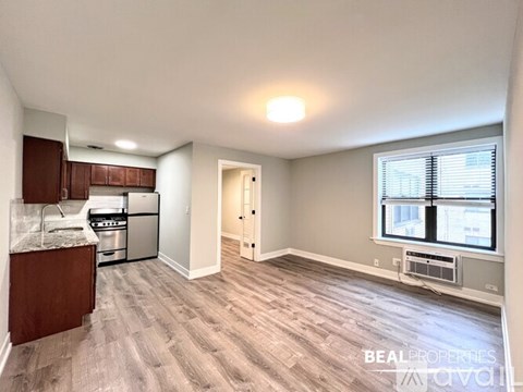 A kitchen with wooden cabinets and a window with blinds.