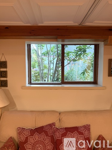 A living room with a couch and a window letting in natural light.