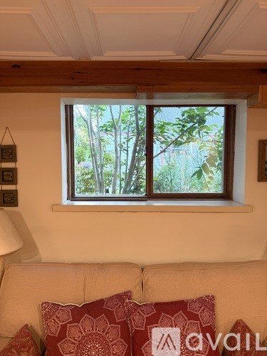 A living room with a couch and a window letting in natural light.