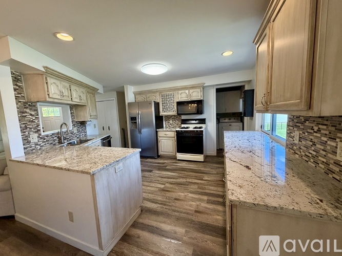 A kitchen with granite countertops and a stone backsplash.