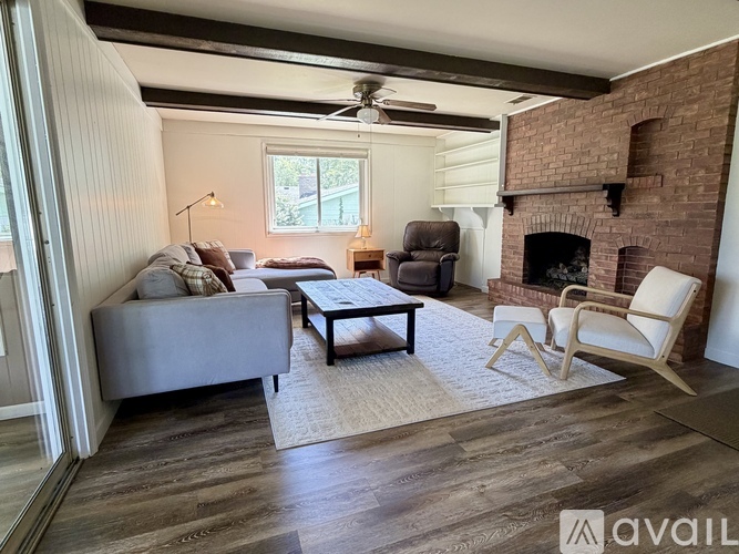 A living room with a grey couch, a brown chair, and a fireplace.