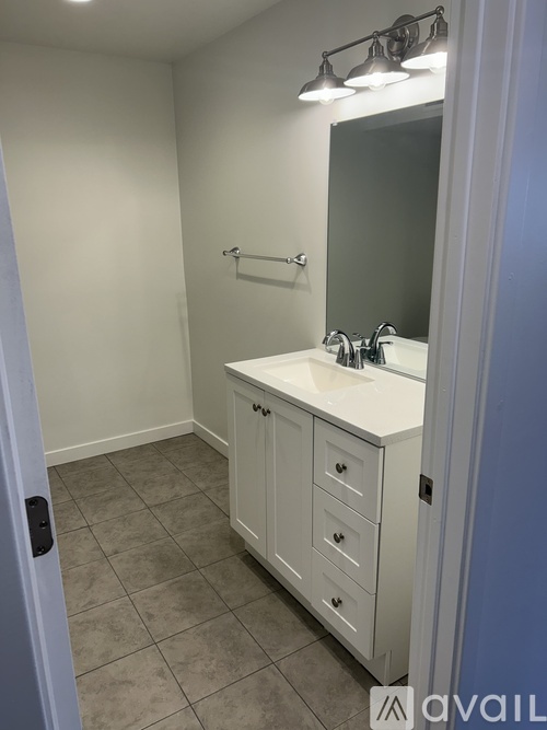 A bathroom with a sink, mirror, and light fixture.