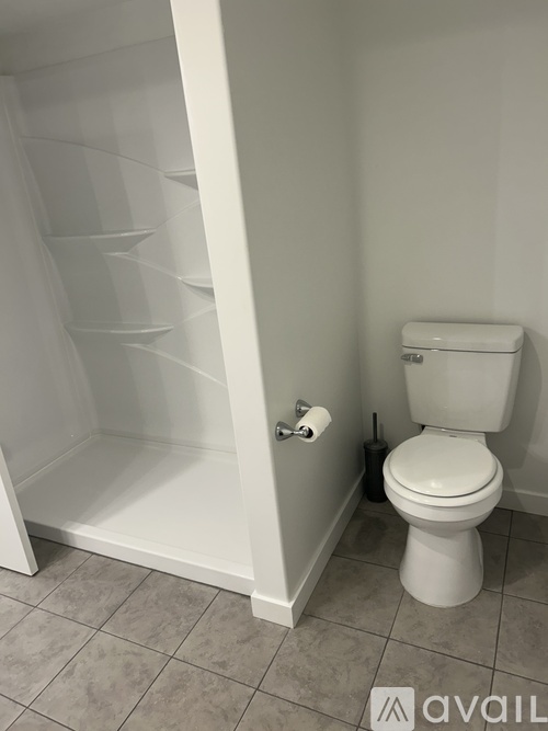 A white toilet sits next to a white shelving unit in a bathroom.