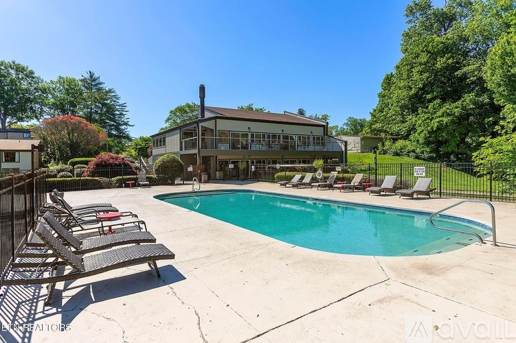 A pool with lounge chairs and a house in the background.